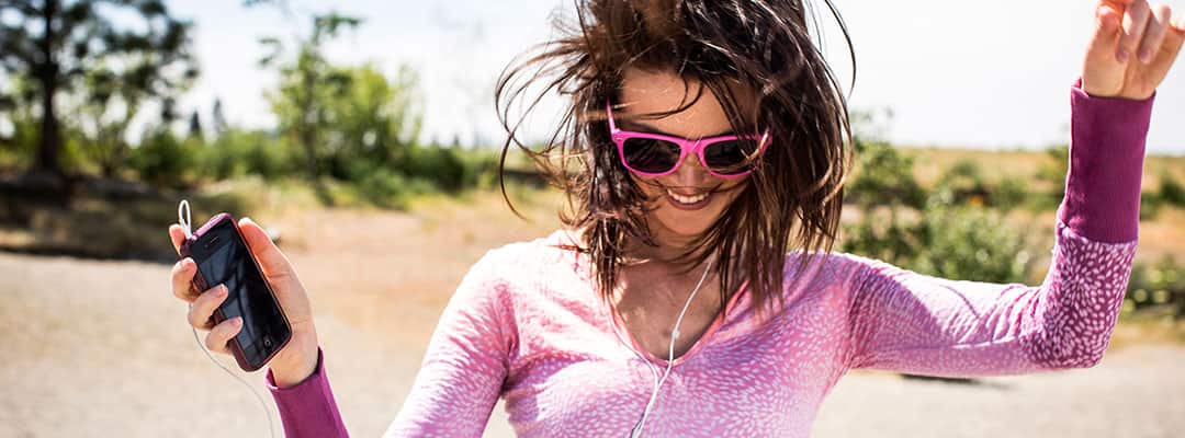 Woman with a boost of energy from supplements listening to music and dancing outdoors