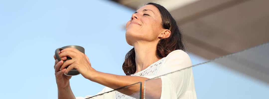 Healthy woman out on the balcony enjoying Ashwagandha’s health benefits