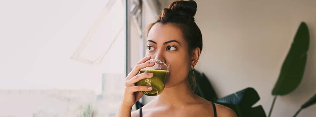 Vegan woman drinking green smoothie that may be nutrient deficient in areas