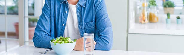 Man sitting at table not wanting to eat healthy food on plate