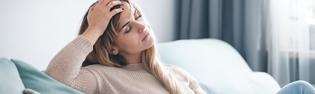 Woman on couch feeling fatigued due to thyroid hormones